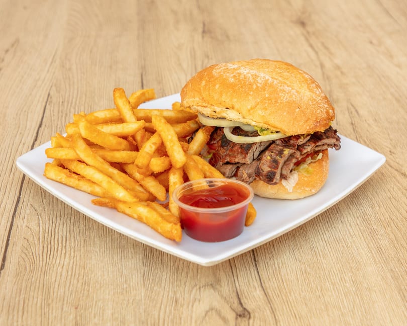 Grilled steak sandwich with onions and lettuce, served with golden french fries and ketchup.